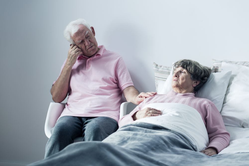 husband supporting elderly wife in bed