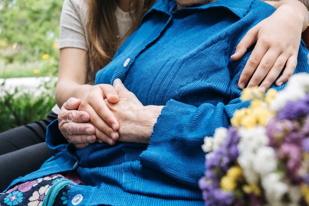 elderly woman being supported by younger woman