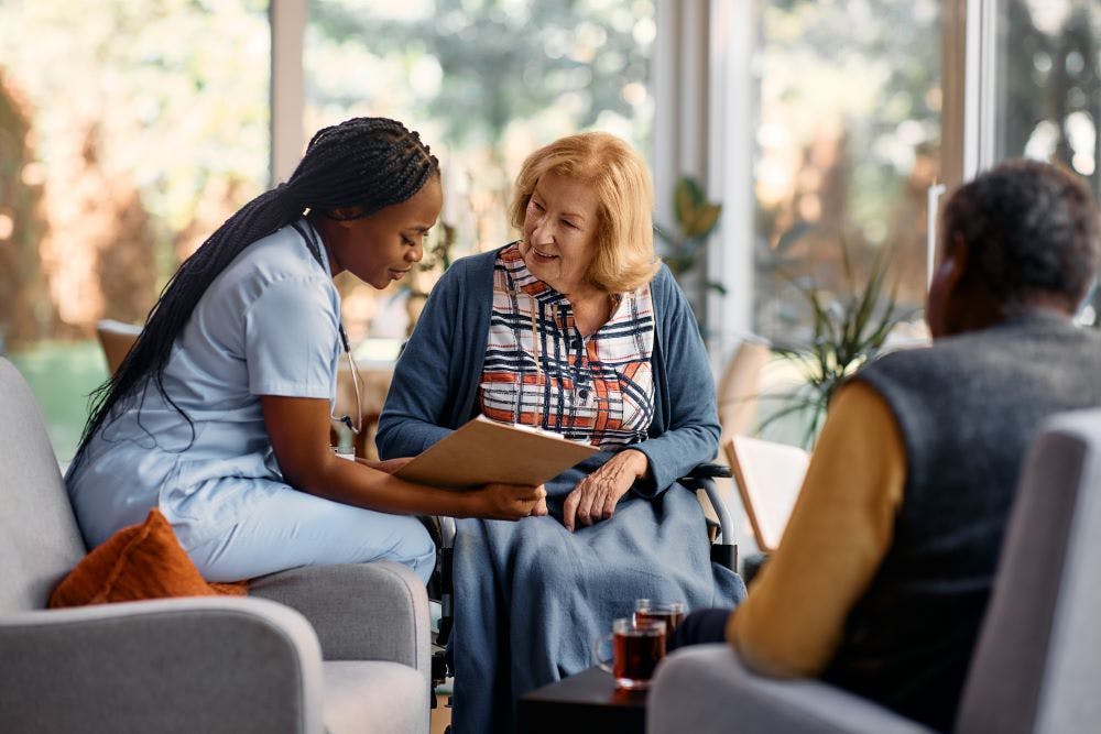 nurse talks to elderly couple in their home