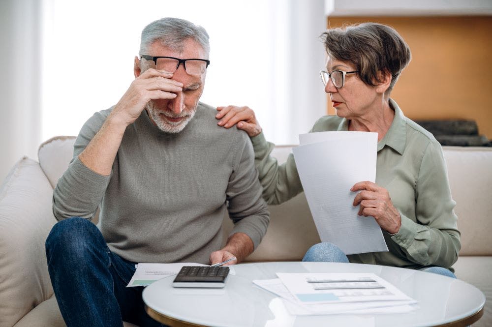 A senior couple looking stressed while reviewing financial documents