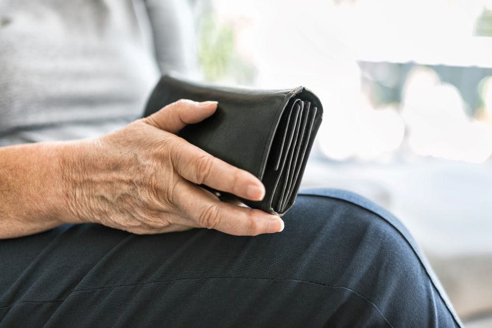 An elderly woman holds a black leather purse